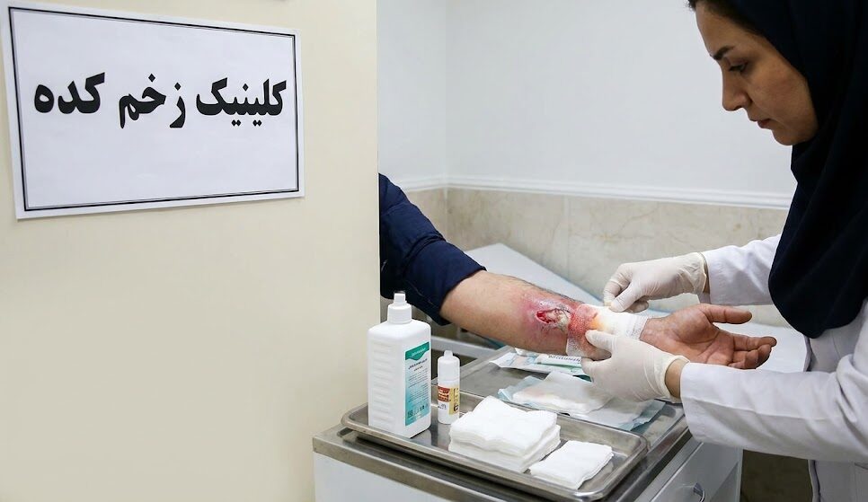 پرستار متخصص در حال انجام پانسمان و مدیریت درمان زخم عفونی فعال روی ساعد بیمار در محیط استریل کلینیک.